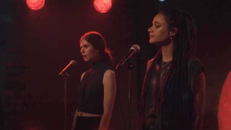 Alison Oliver as Frances Flynn and Sasha Lane as Bobbi Connolly standing on an open mic stage on Conversations with Friends