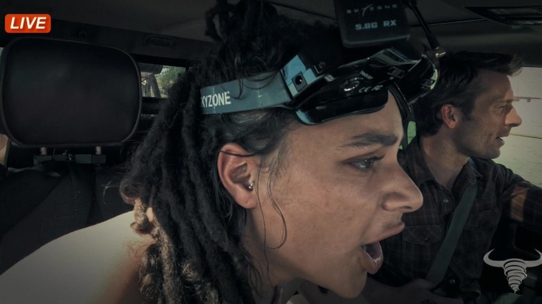 Sasha Lane as Lily and Glen Powell as Tyler Owens seen through a fisheye live cam inside a car in Twisters