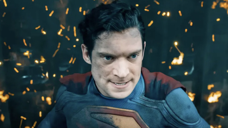 David Corenswet as Kal-El / Clark Kent / Superman with a singed suit standing in from of flames in Superman (2025)