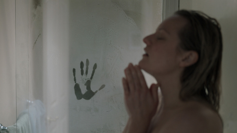 Elisabeth Moss as Cecilia "Cee" Kass taking a shower with her eyes closed next to a scary handprint on the shower door in The Invisible Man (2020)