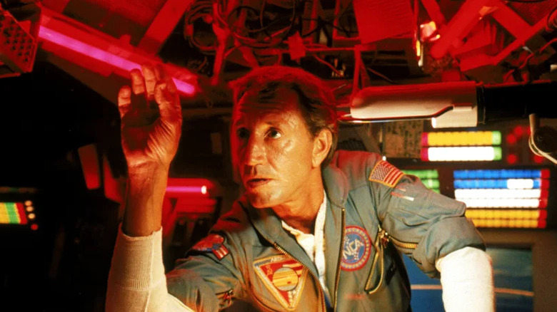 Heywood Floyd (Roy Scheider) reaches for a panel in a command module in 2010: The Year We Make Contact