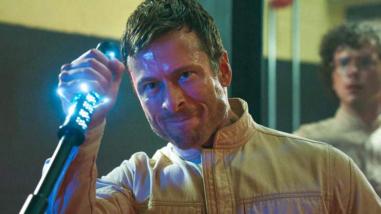 Ben Richards squeezing the business end of a cattle prod, wincing angrily, in The Running Man