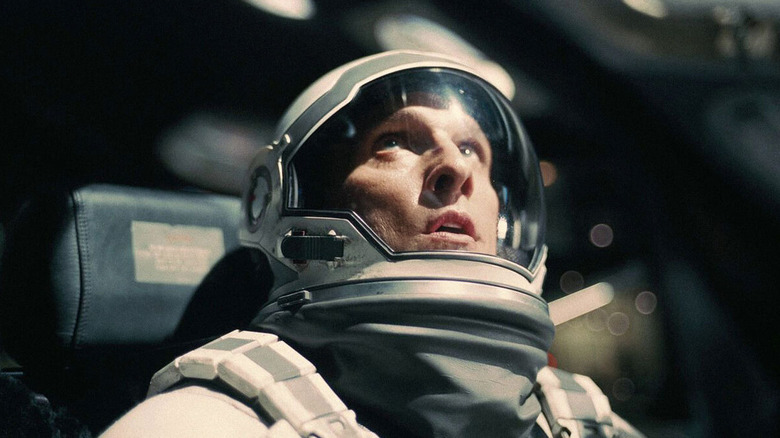 Matthew McConaughey as Joseph "Coop" Cooper in Interstellar, in his astronaut gear on his ship, looking up at something above his head.