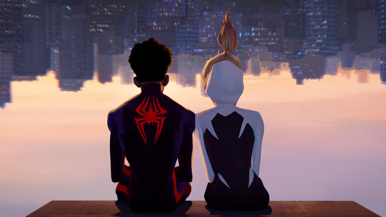 Shameik Moore as Miles Morales/Spider-Man and Hailee Steinfeld as Gwen Stacy in Spider-Man: Across the Spider-Verse, seen from behind as they sit next to each other upside-down, looking at the cityscape.