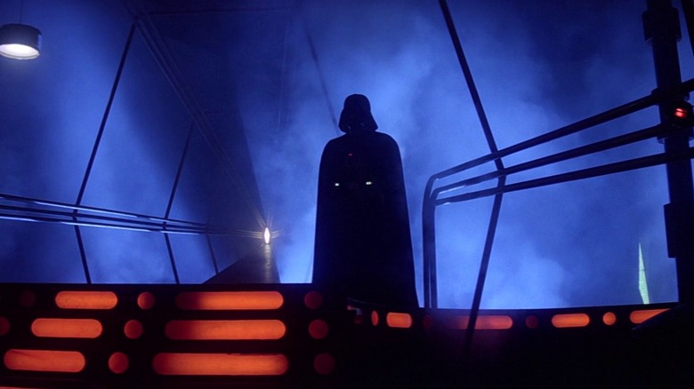 David Prowse/James Earl Jones as Darth Vader, silhouetted against the blue fog on a platform in a ship.