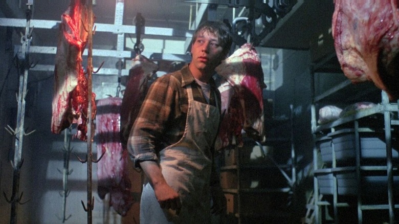 Sam Raimi as Randy in Intruder, standing in a meat freezer with some slabs of meat hooked up around him.