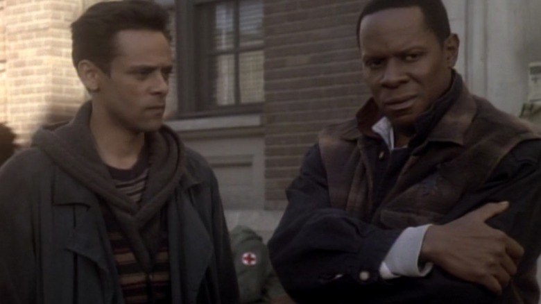 Julian Bashir (Alexander Siddig) and Benjamin Sisko (Avery Brooks) stand in a street wearing 21st century clothes in Star Trek: Deep Space Nine