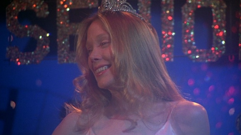 Sissy Spacek as Carrie White in Carrie, standing with a prom queen crown on while smiling and looking out.