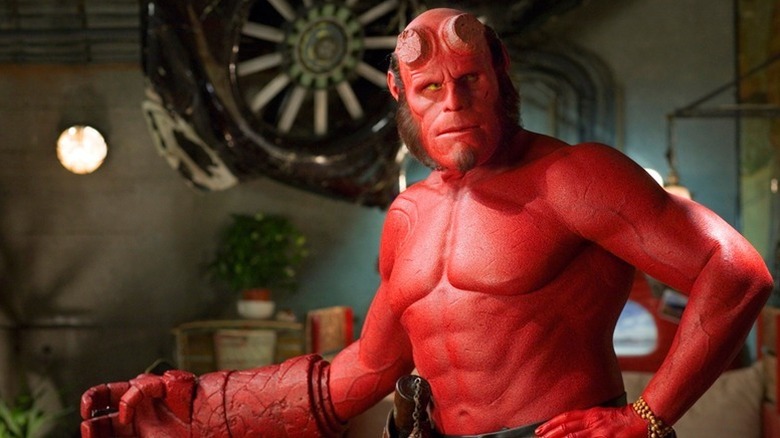 Hellboy (Ron Perlman) stands topless with his hand outstretched in Hellboy (2004)