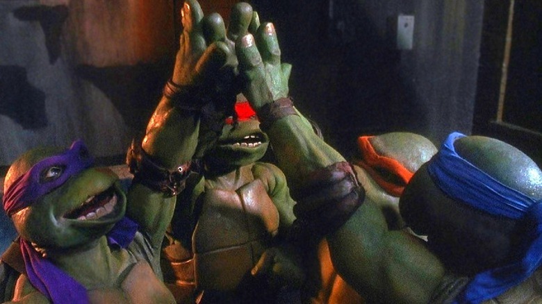 The Ninja Turtles high five in Teenage Mutant Ninja Turtles (1990)