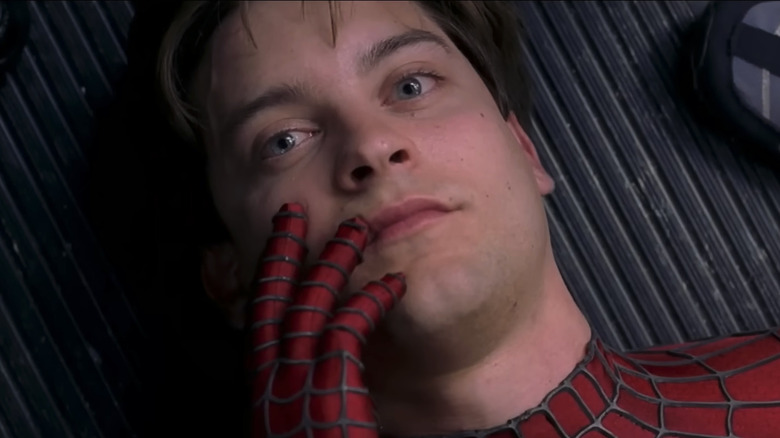 Tobey Maguire as Peter Parker, touching his unmasked face on a train, in Spider-Man 2