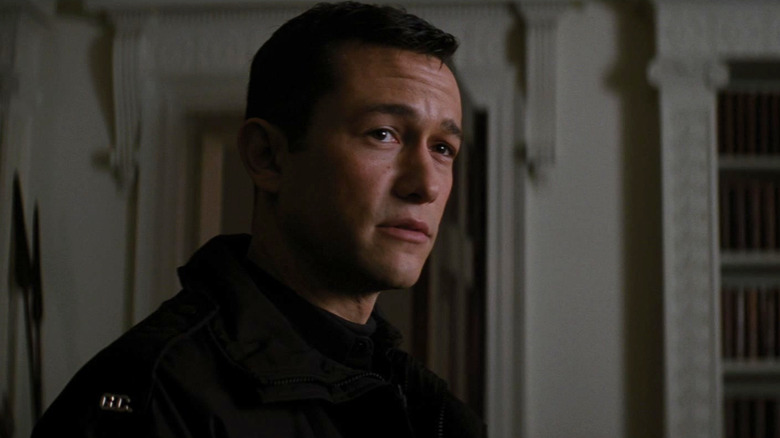 Joseph Gordon-Levitt as John Blake, sitting on a couch, in The Dark Knight Rises