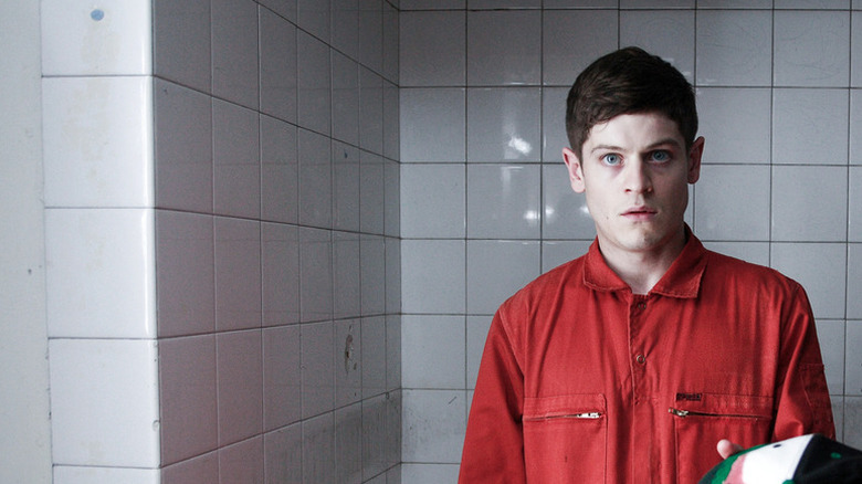 Simon Bellamy (Iwan Rheon) stands wearing a community service uniform in Misfits