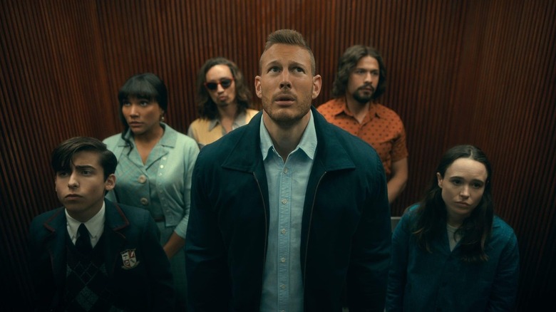 Number Five (Aidan Gallagher), Allison Hargreeves (Emmy Raver-Lampman), Klaus Hargreeves (Robert Sheehan), Luther Hargreeves (Tom Hopper), Diego Hargreeves (David Castañeda), and Vanya Hargreeves (Elliot Page) stand awkwardly in an elevator in The Umbrella Academy