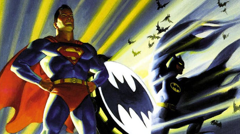 Superman and Batman pose next to the Bat Signal