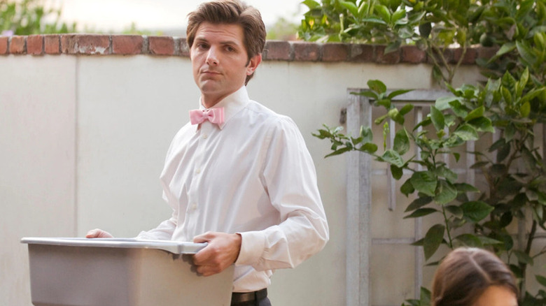 Henry Pollard (Adam Scott) nonchalantly holds a plastic bin while in his caterer uniform in Party Down