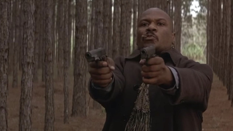 Ving Rhames as Mann shooting two guns in the woods in Rosewood
