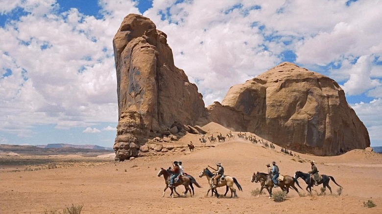 a group of cowboys being shadowed by Native Americans against the backdrop of Monument Valley in The Searchers