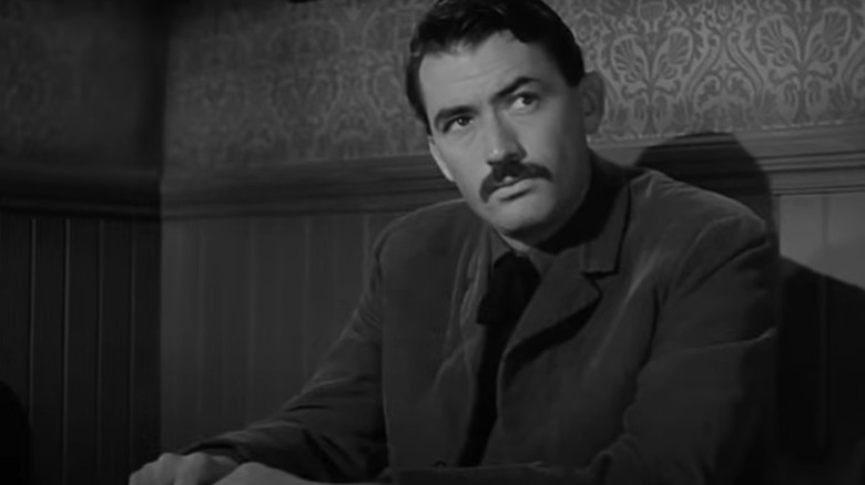 Jimmy Ringo (Gregory Peck) sits pensively against a wall in The Gunfighter (1950)