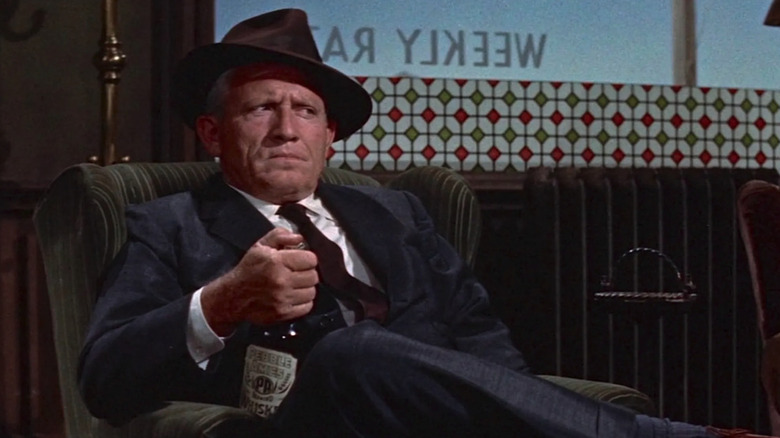John J. Macreedy (Spencer Tracy) scowls in a chair with a bottle of whiskey in his hand in Bad Day at Black Rock