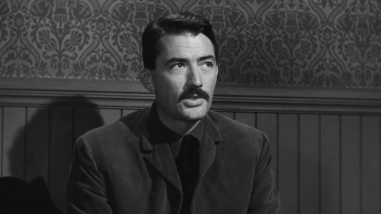 Jimmy Ringo (Gregory Peck) sits pensively against a wall in The Gunfighter (1950)