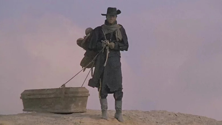 Django (Franco Nero) walks through a desert dragging a casket in Django (1966)