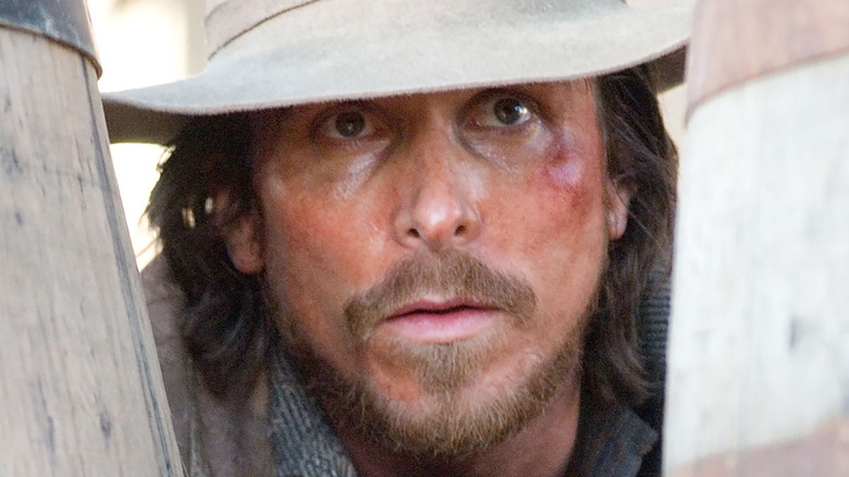 Christian Bale as Dan Evans looking between two barrels in 3:10 to Yuma (2007)