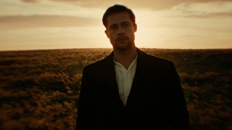 Brad Pitt as Jesse James in The Assassination of Jesse James by the Coward Robert Ford, standing against an open field with ethereal lighting and a blur.