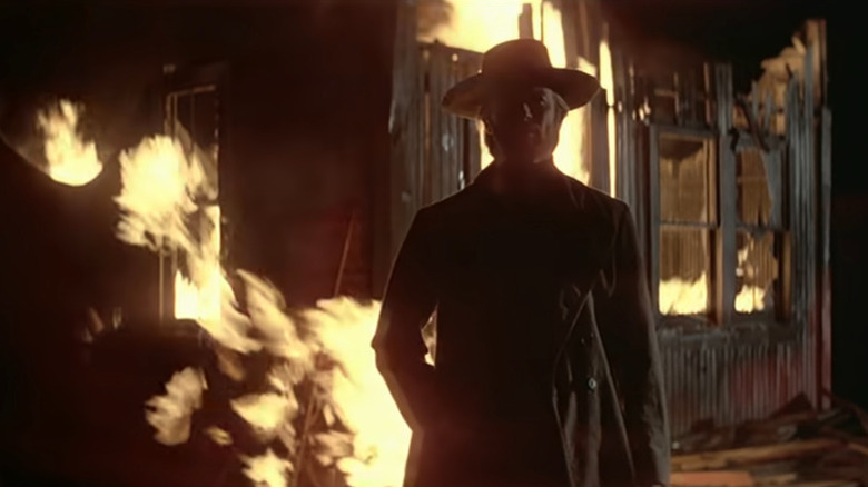 The stranger (Clint Eastwood) stands by a burning building in High Plains Drifter