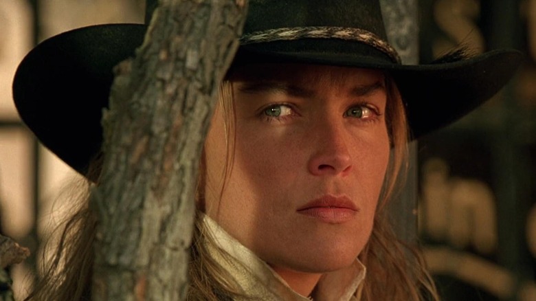 The Lady (Sharon Stone) glares behind a slender tree trunk in The Quick and the Dead (1995)