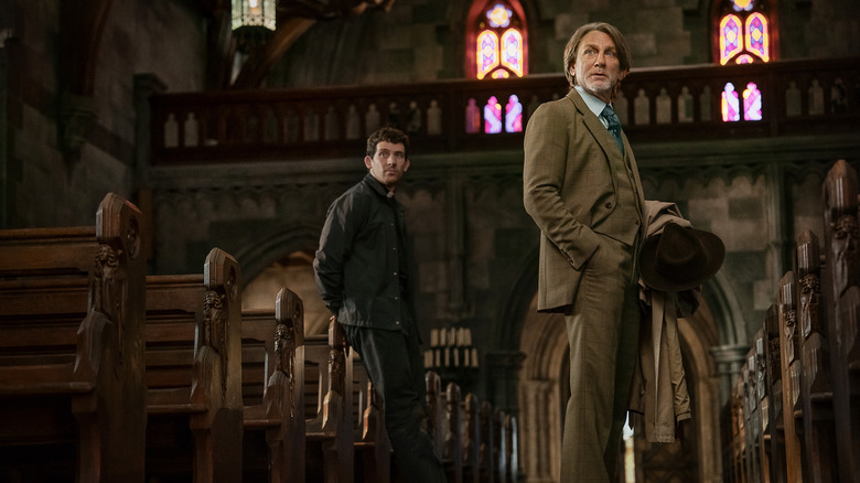 Jud Duplenticy (Josh O'Connor) and Benoit Blanc (Daniel Craig) stand in between church pews in Wake Up Dead Man: A Knives Out Mystery