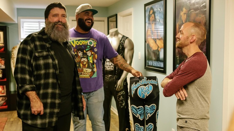Mick Foley, AJ Francis, and a WWE fan admire some memorabilia in WWE's Most Wanted Treasures