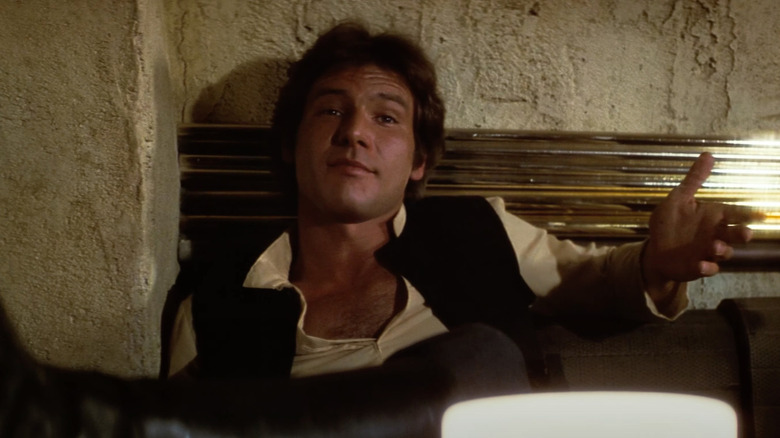 Harrison Ford as Han Solo smirks behind a bar in Star Wars