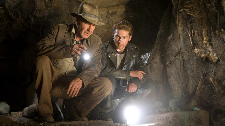 Harrison Ford as Indiana Jones crouches next to Shia LaBeouf as Mutt Williams in Indiana Jones and the Kingdom of the Crystal Skull