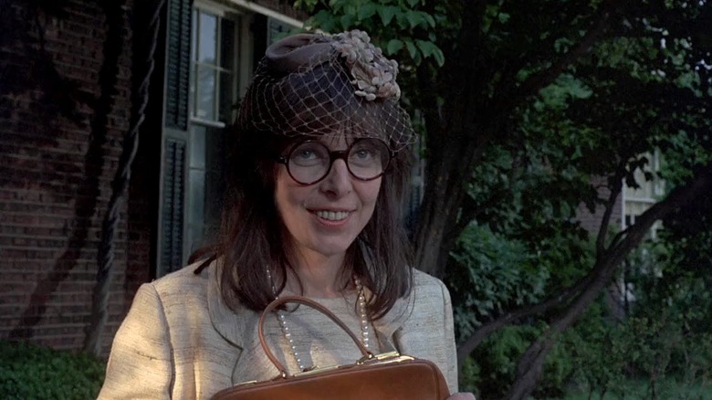 Elaine May as Henrietta Lowell in A New Leaf, wearing unbefitting round glasses, offering a grin while looking off at something.