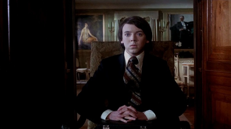 Bud Cort as Harold Parker Chasen in Harold and Maude, sitting in a very nice looking house in a suit and tie, looking concerned off out of frame.