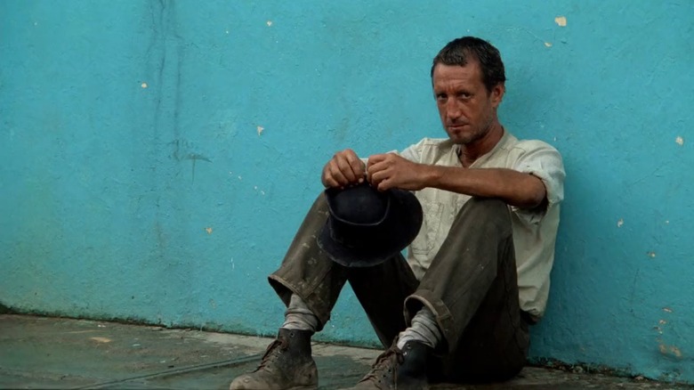 Roy Scheider as Jackie Scanlon in Sorcerer, looking really dirty and sitting against a blue wall.