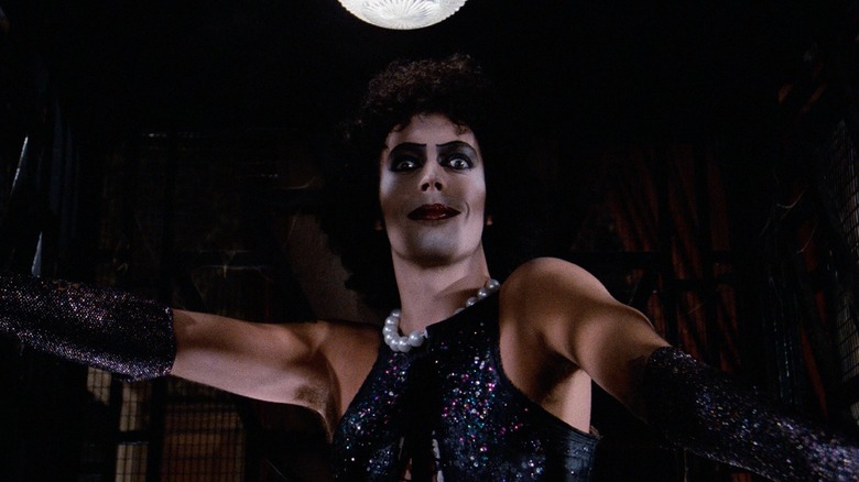 Tim Curry as Dr. Frank-N-Furter in The Rocky Horror Picture Show, donning the slinky glam garb and looking intently into the camera.