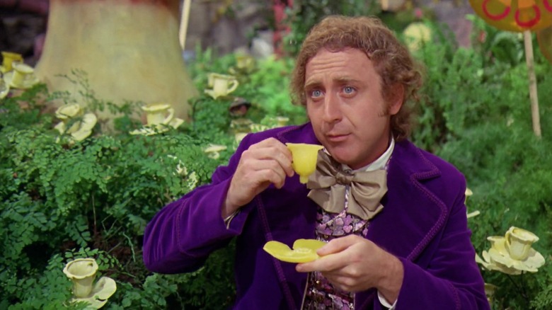 Gene Wilder as Willy Wonka in Willy Wonka and the Chocolate Factory, sipping from a flower petal tea cup in the factory's garden.