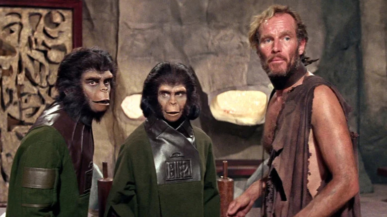Cornelius (Roddy McDowall), Zira (Kim Hunter), and George Taylor (Charlton Heston) stand together in Planet of the Apes (1968)