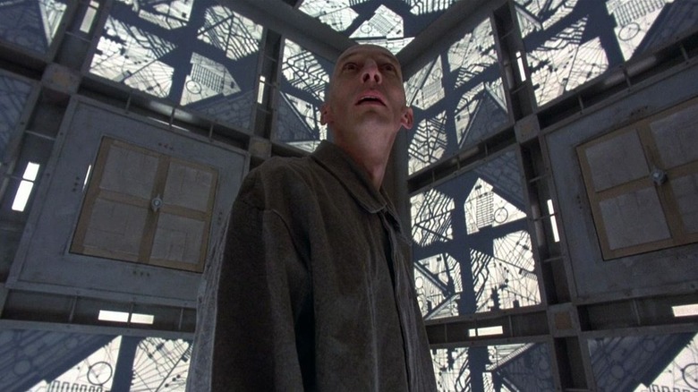 Julian Richings as Alderson looking upward inside a patterned room in Cube