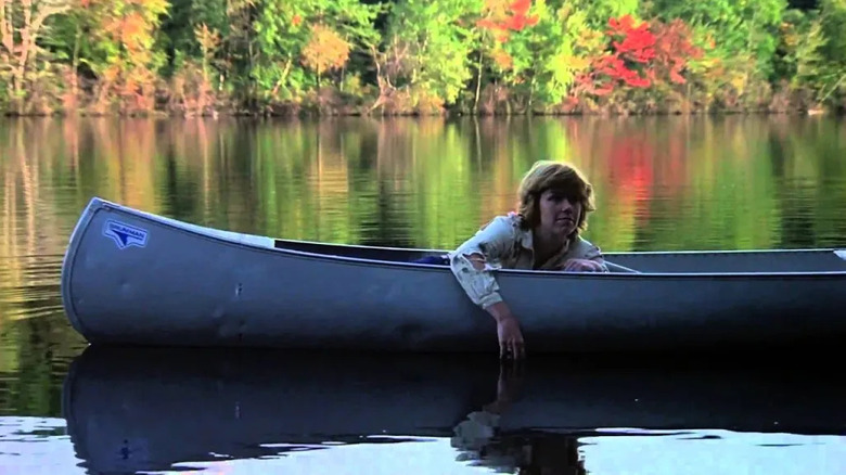 Adrienne King as Alice Hardy sitting in a boat with her arm hanging off the side in a still lake surrounded by trees in Friday the 13th