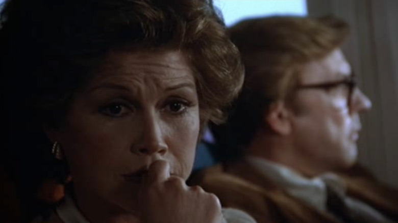 Mary Tyler Moore looks concerned as Beth on a plane with Donald Sutherland as Calvin in the background in Ordinary People