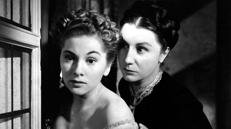 Joan Fontaine looking frightened with Judith Anderson as Mrs. Danvers standing menacingly behind her