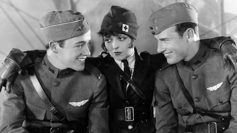 Charles Rogers as Jack and Richard Arlen as David in military uniforms smiling on either side of Clara Bow as Mary in medic uniform in Wings