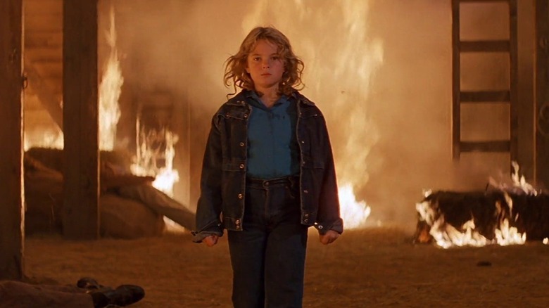 Charlie (Drew Barrymore) stands in front of a burning building in Firestarter