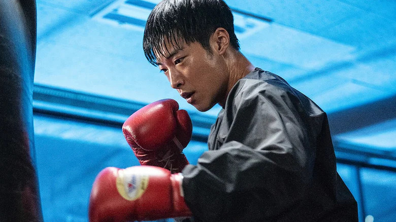Kim Geon-woo (Woo Do-hwan) punches a heavy bag with boxing gloves on in Bloodhounds