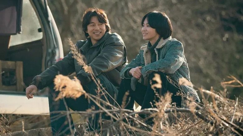 Dong-gu (Gong Yoo) and Min-ja (Song Hye-kyo) sit smiling together next to a van in Tantara