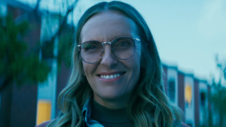 Toni Collette as Evelyn Wade, smiling in front of a school in Wayward