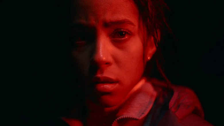 A close-up of Lou Llobell as Maddie Brecker in Passenger, bathed in red light.